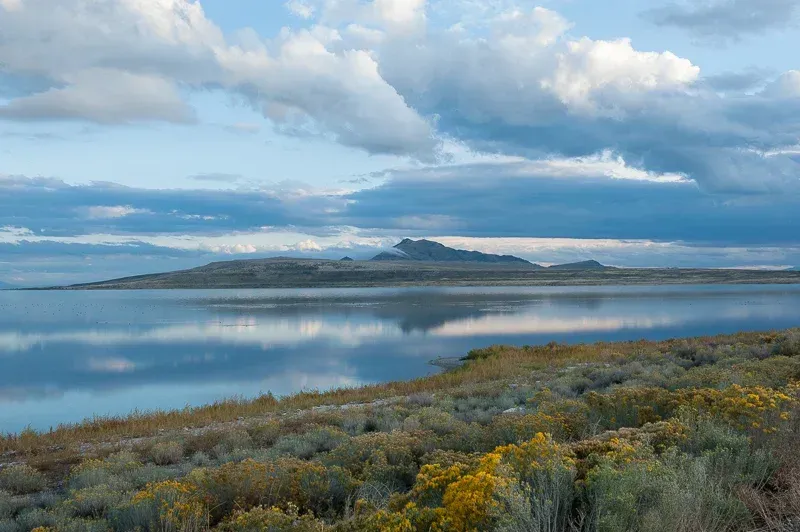 A large body of water with mountains in the background and a cloudy sky.