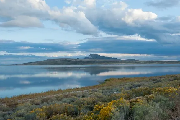 A large body of water with mountains in the background and a cloudy sky.