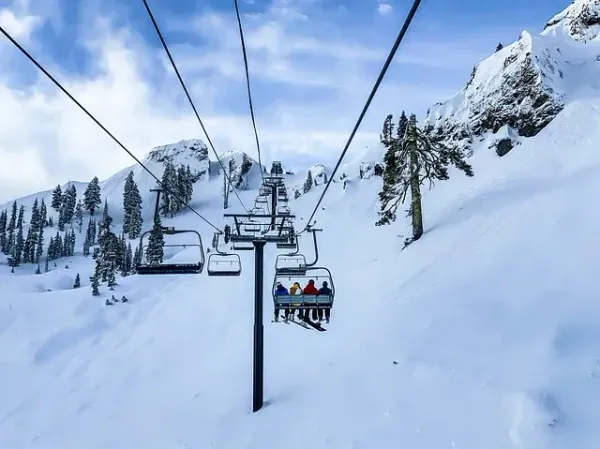 A ski lift carrying people up a snow covered mountain.