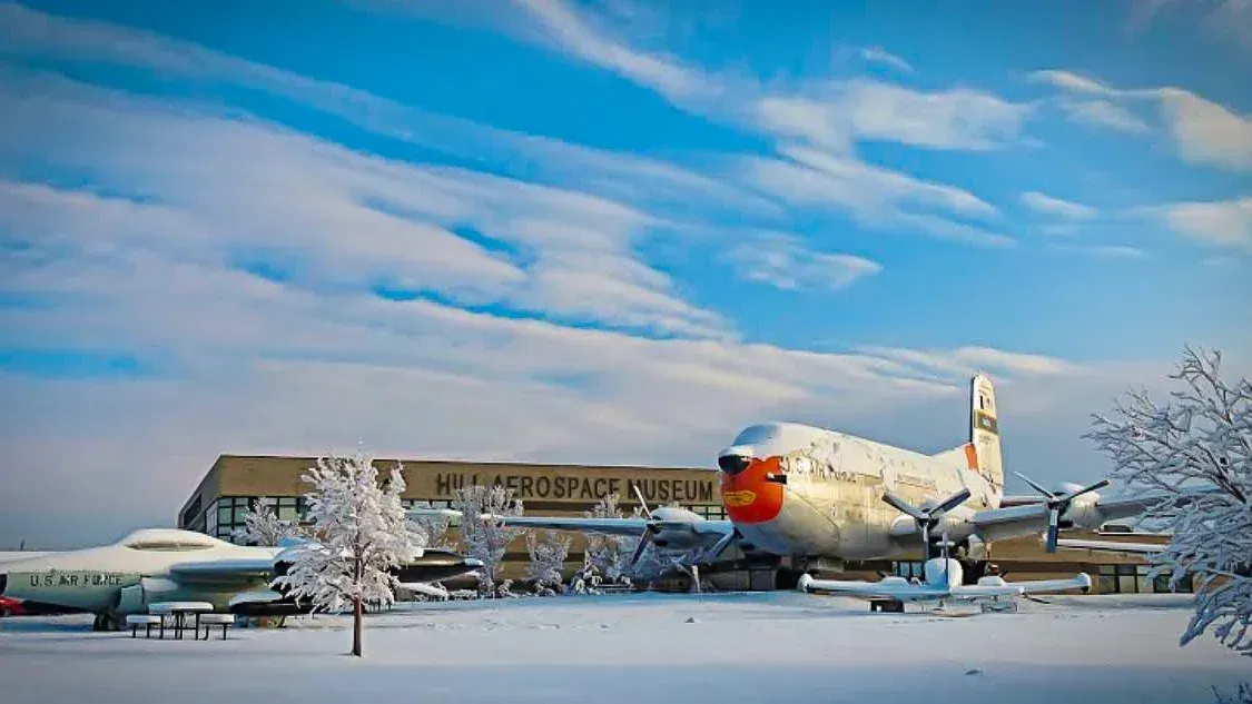 A large airplane is parked in the snow in front of a building.