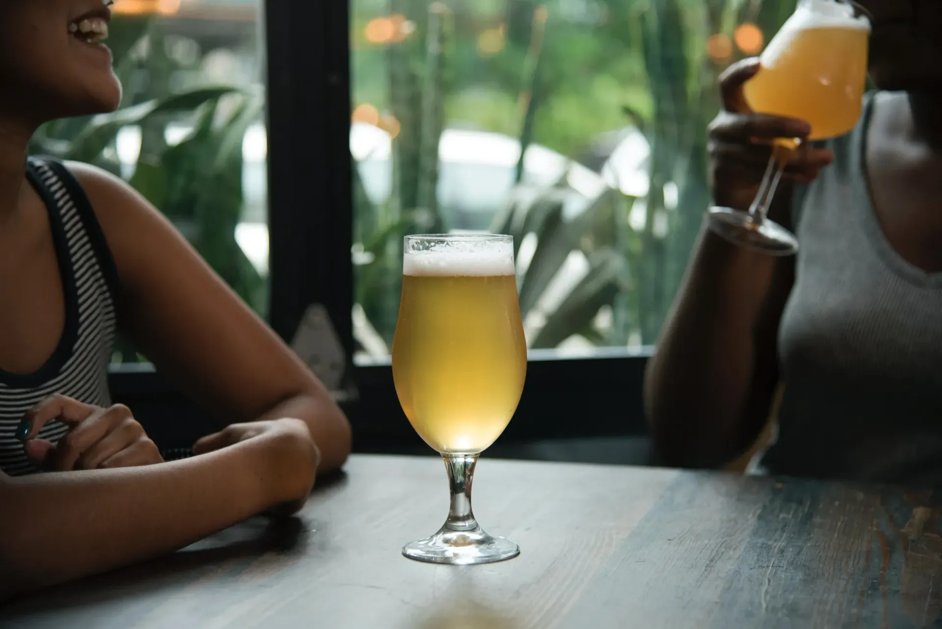 Two women are sitting at a table drinking beer.