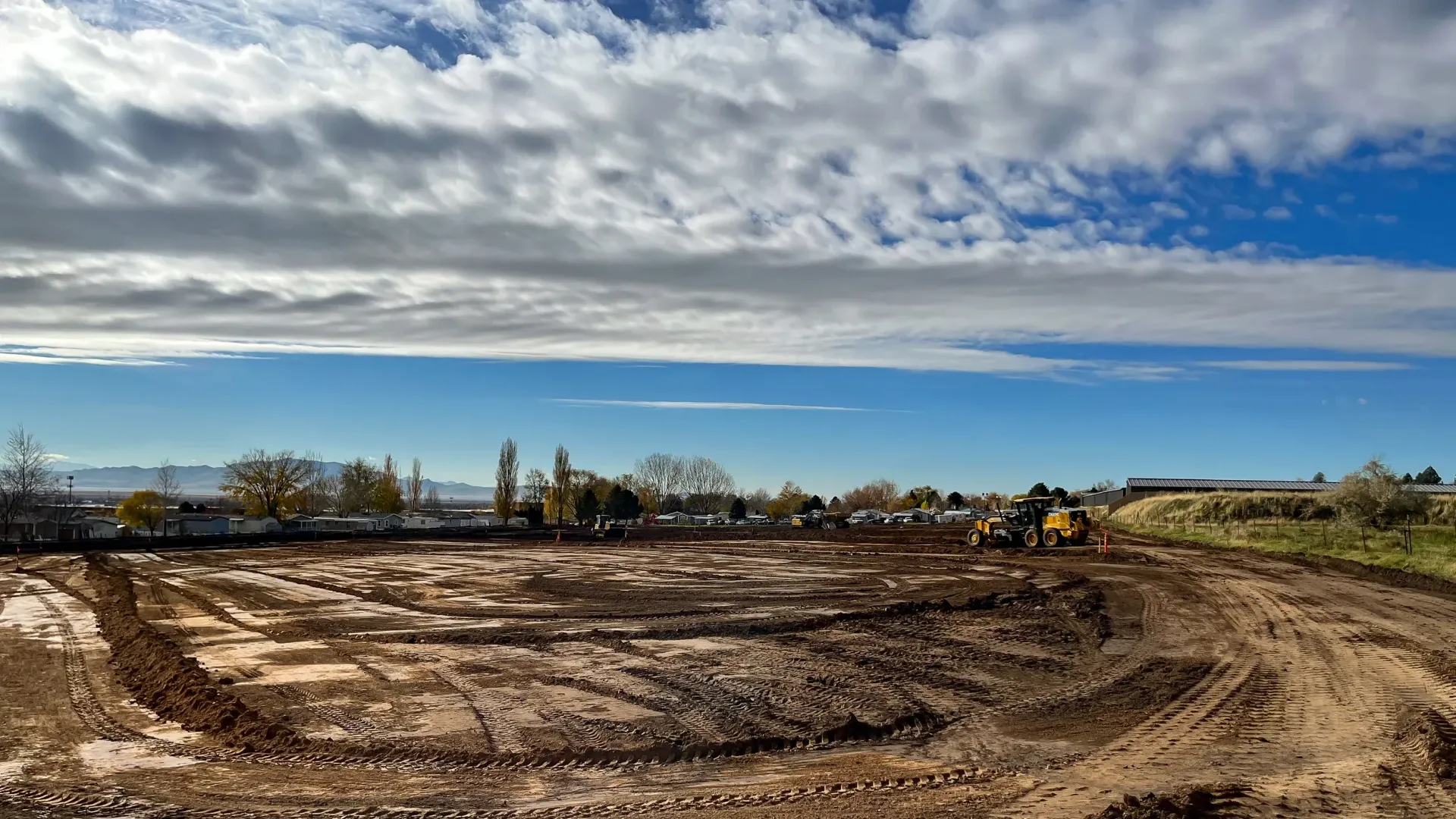 A large dirt field with a blue sky and clouds in the background.
