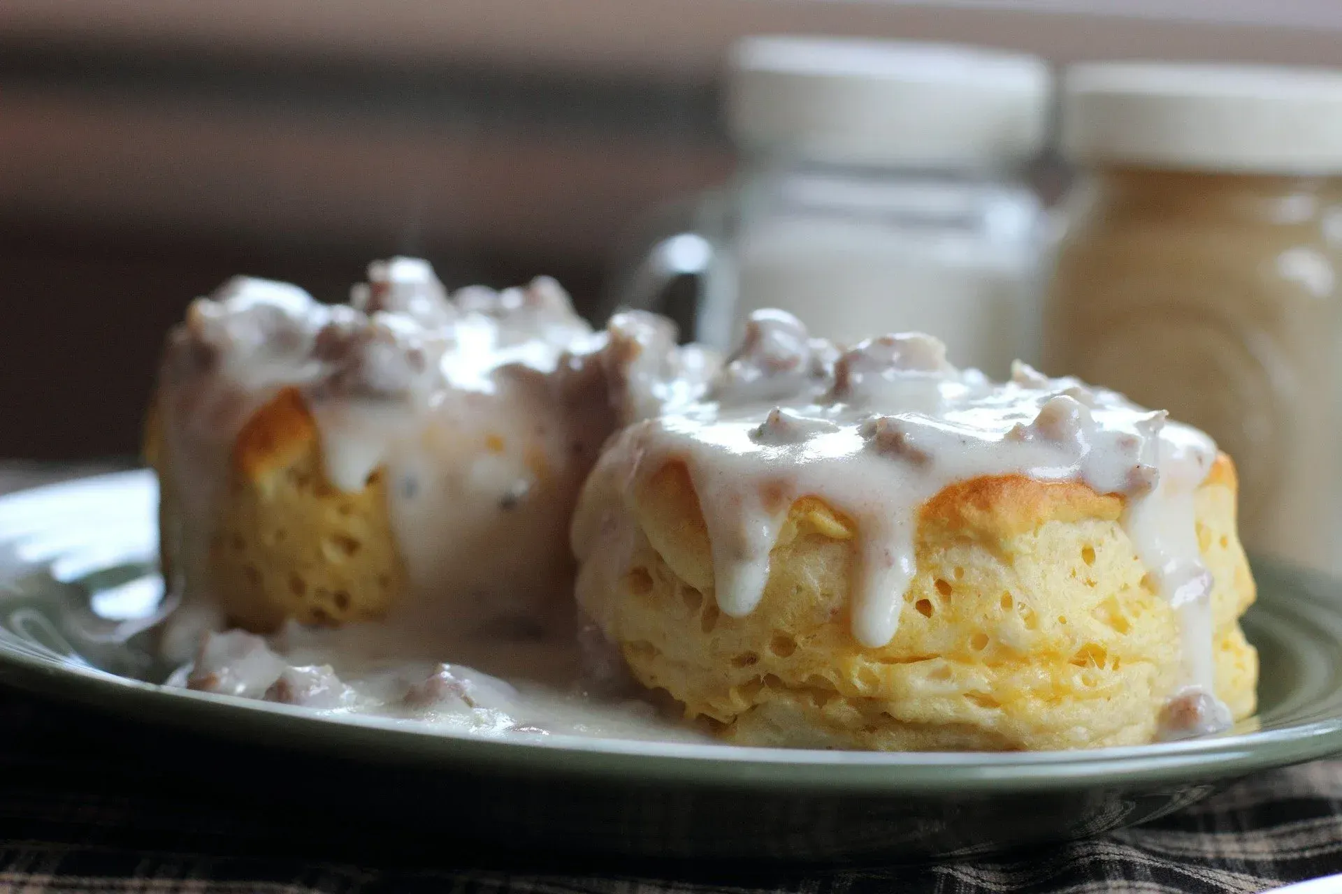 Two biscuits with gravy on a green plate