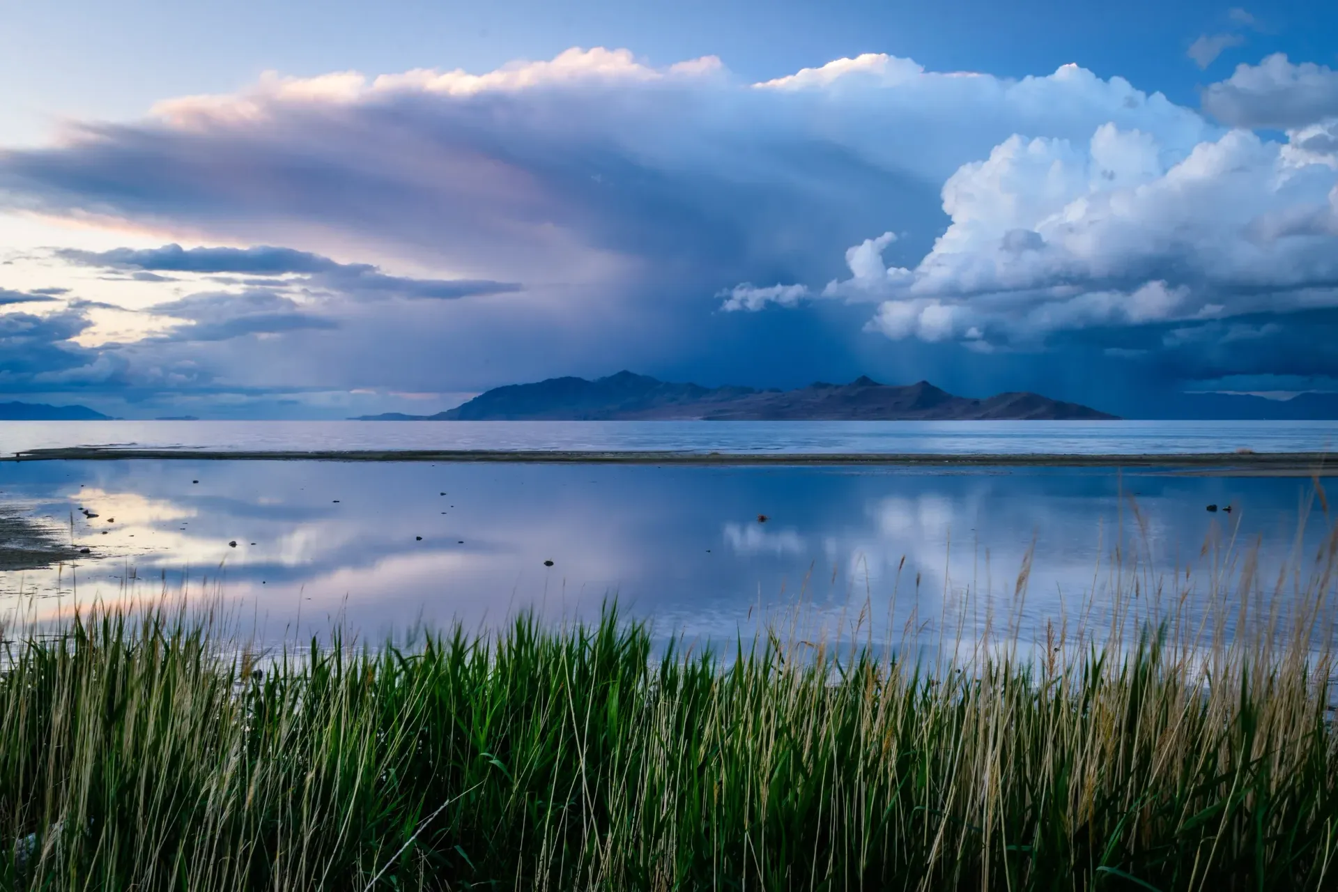 A lake with mountains in the background and a cloudy sky