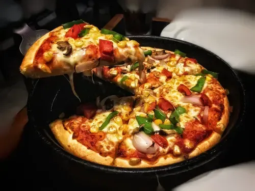 A person is taking a slice of pizza from a pizza pan.