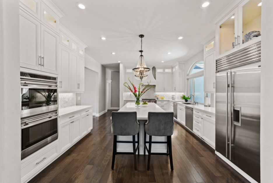 a kitchen with white cabinets and stainless steel appliances and a large island .