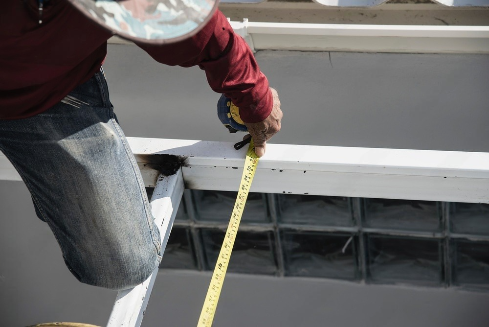 a man is measuring a gutter with a tape measure