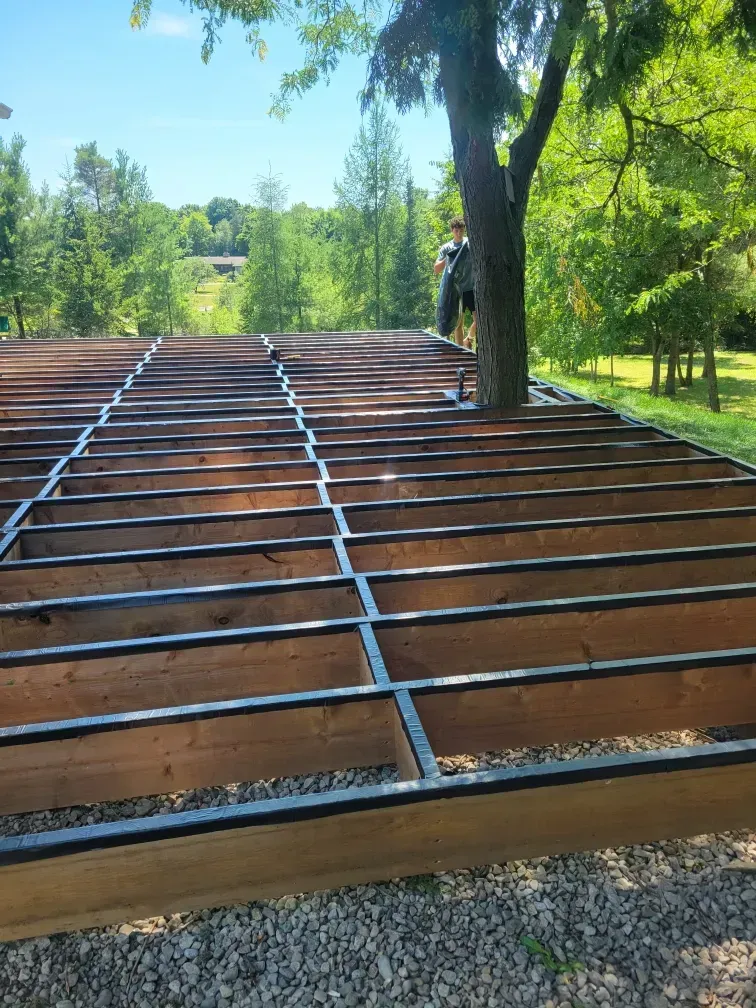 Wooden deck frame under construction with a tree growing through it; outdoors.