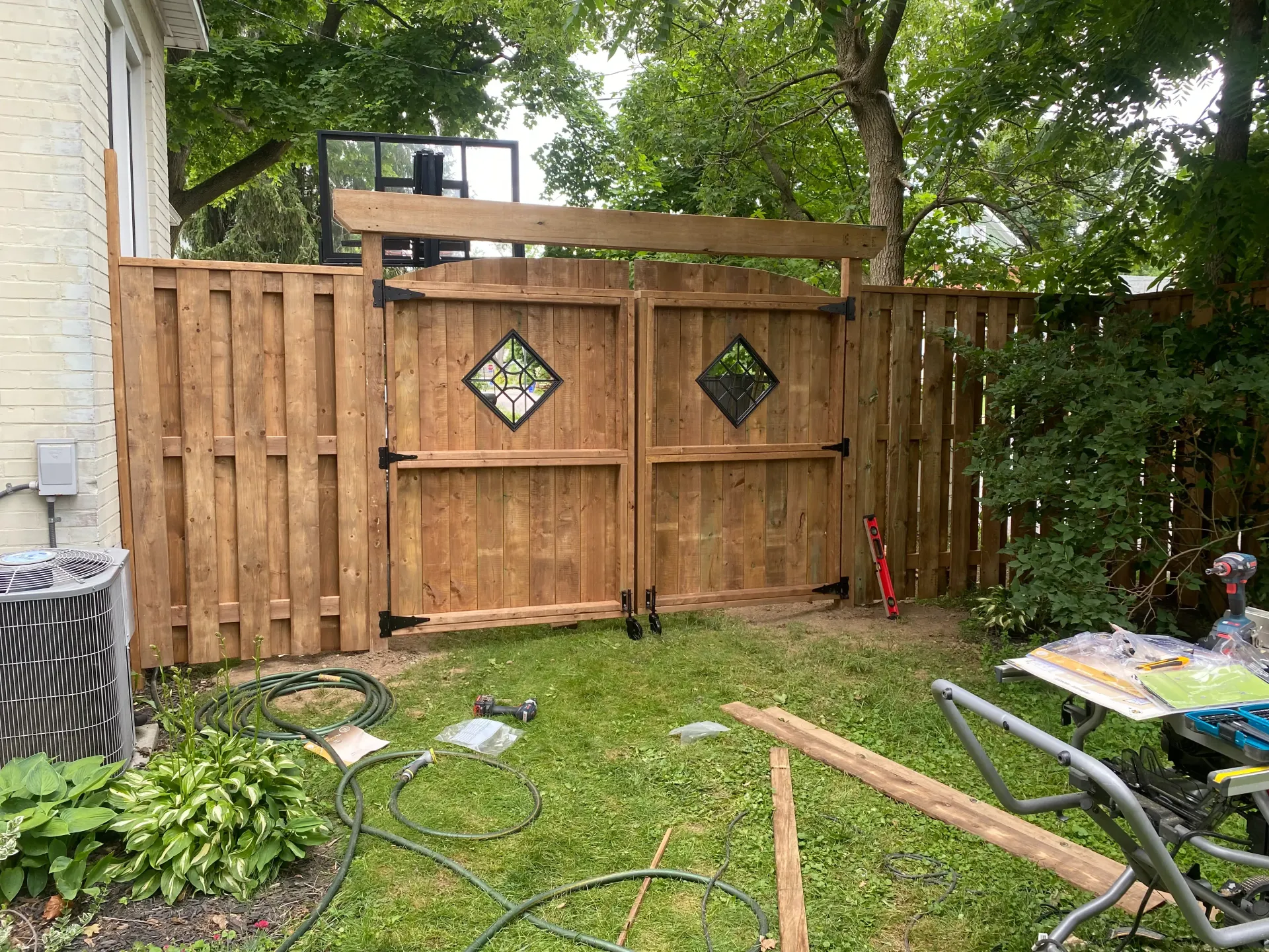 Wooden fence with double gate, decorative diamond inlays. Basketball hoop visible above.