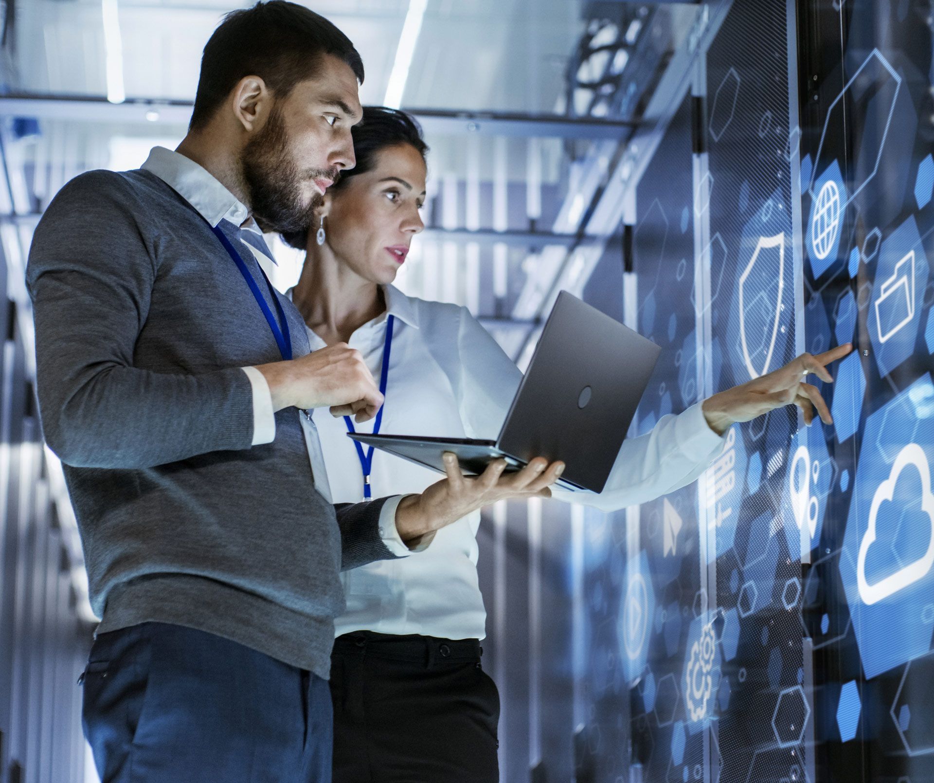 A man and a woman are looking at a laptop in a server room