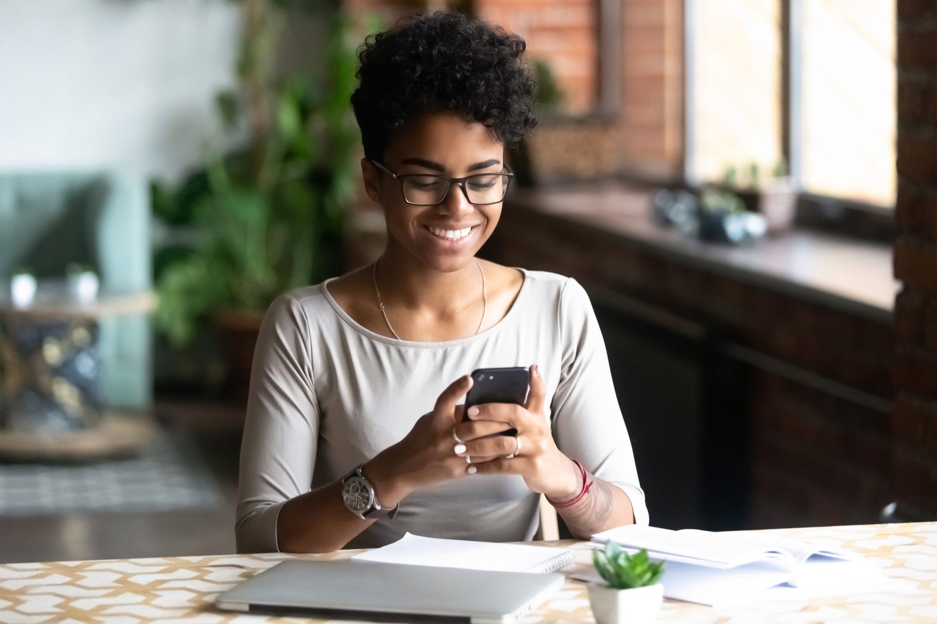 A woman is sitting at a table looking at her cell phone.