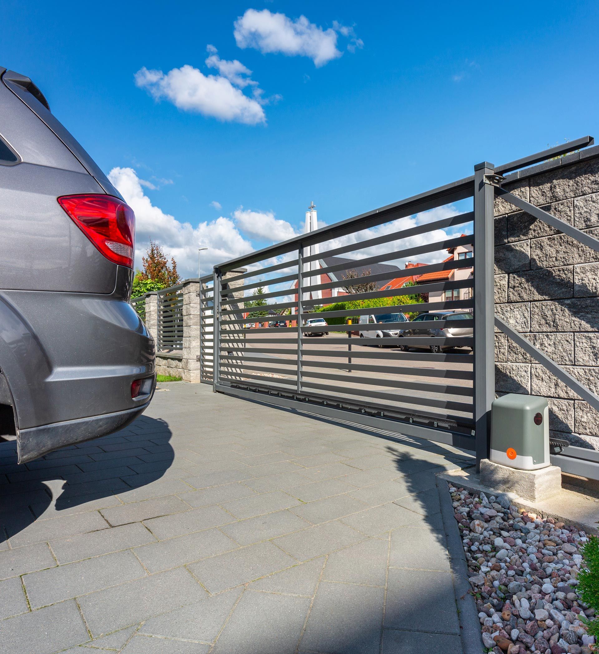 A car is parked in front of a sliding gate.