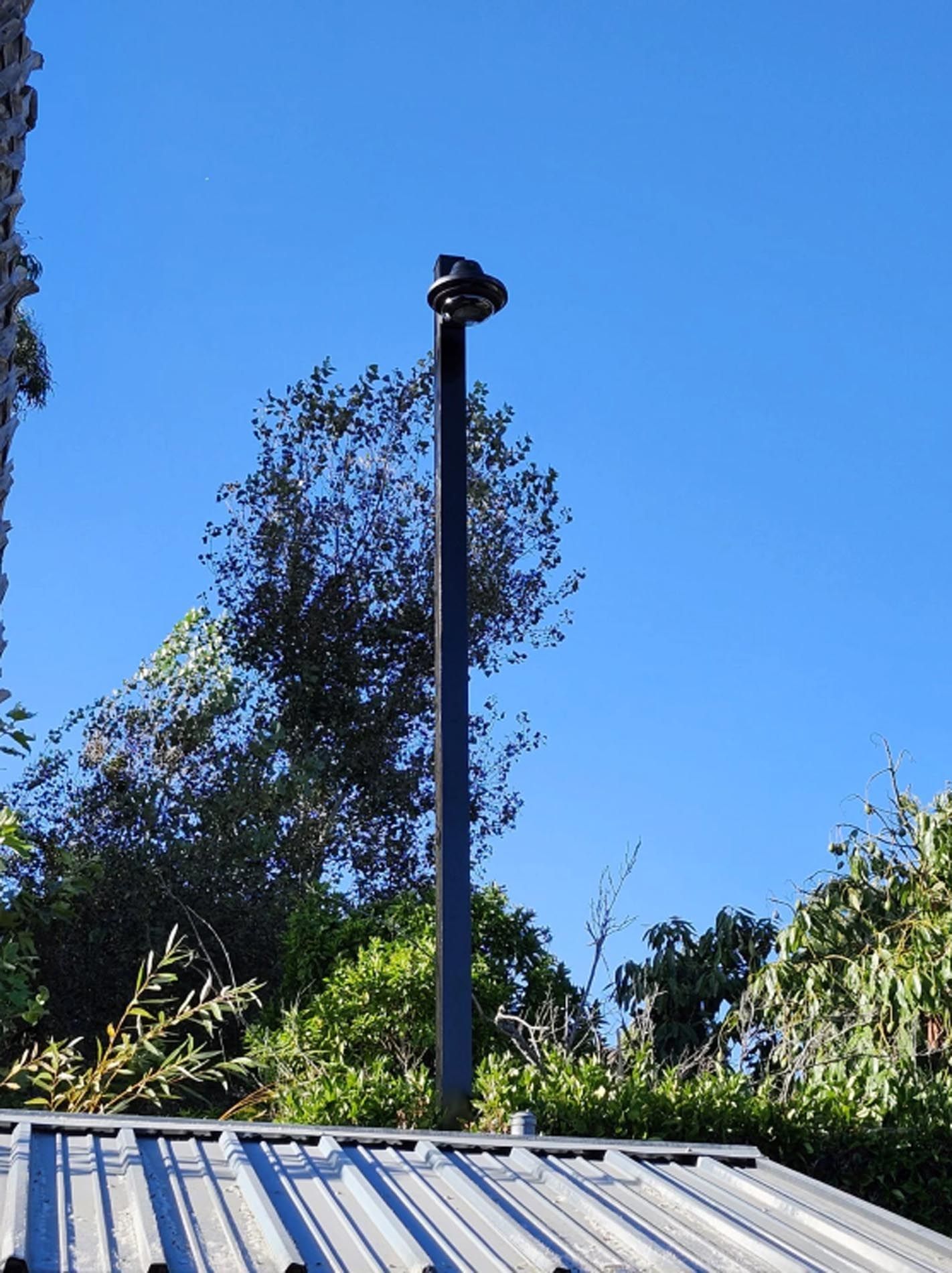 A chimney on top of a metal roof with trees in the background
