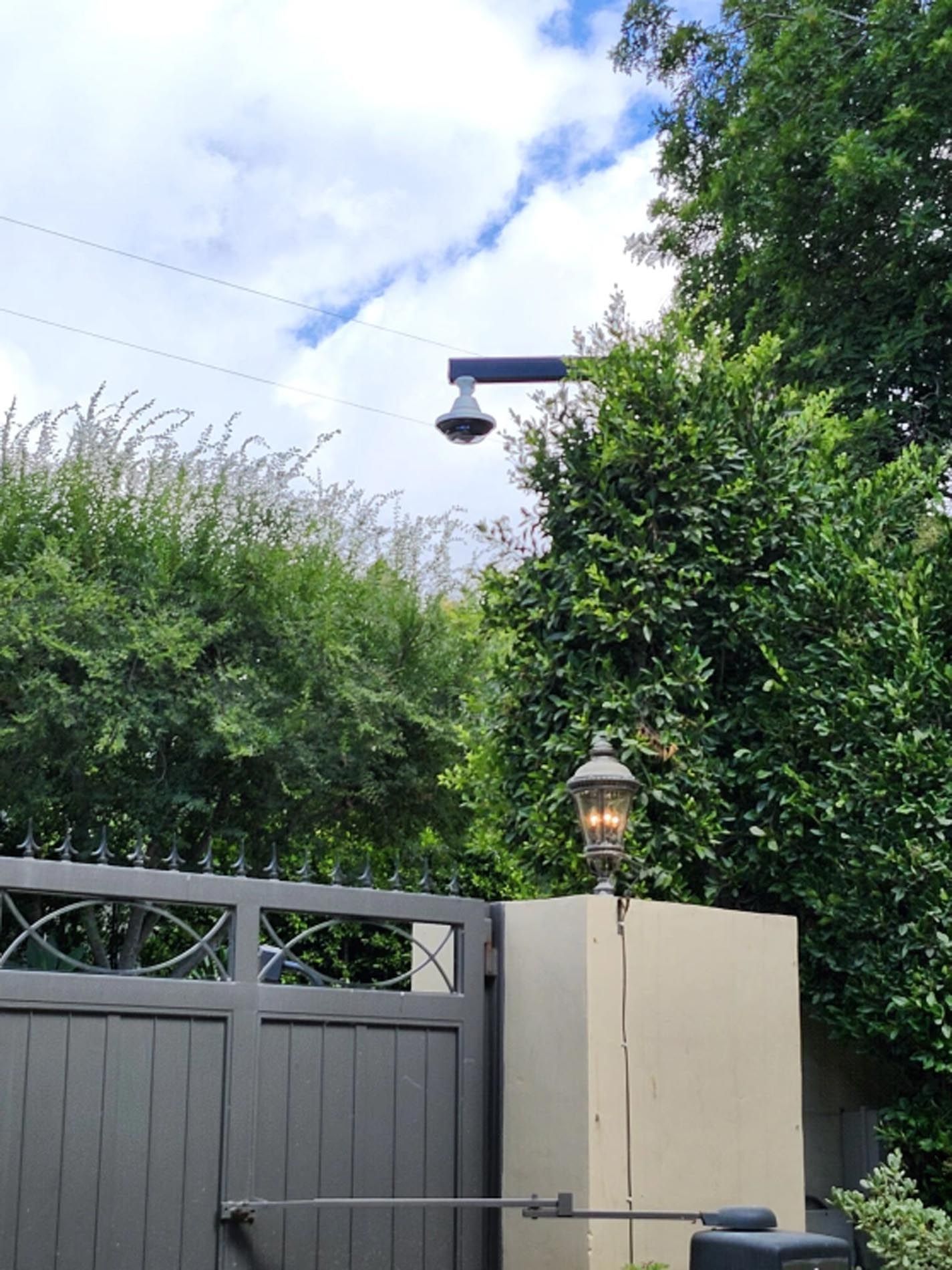 A black gate with a lamp on the side of it