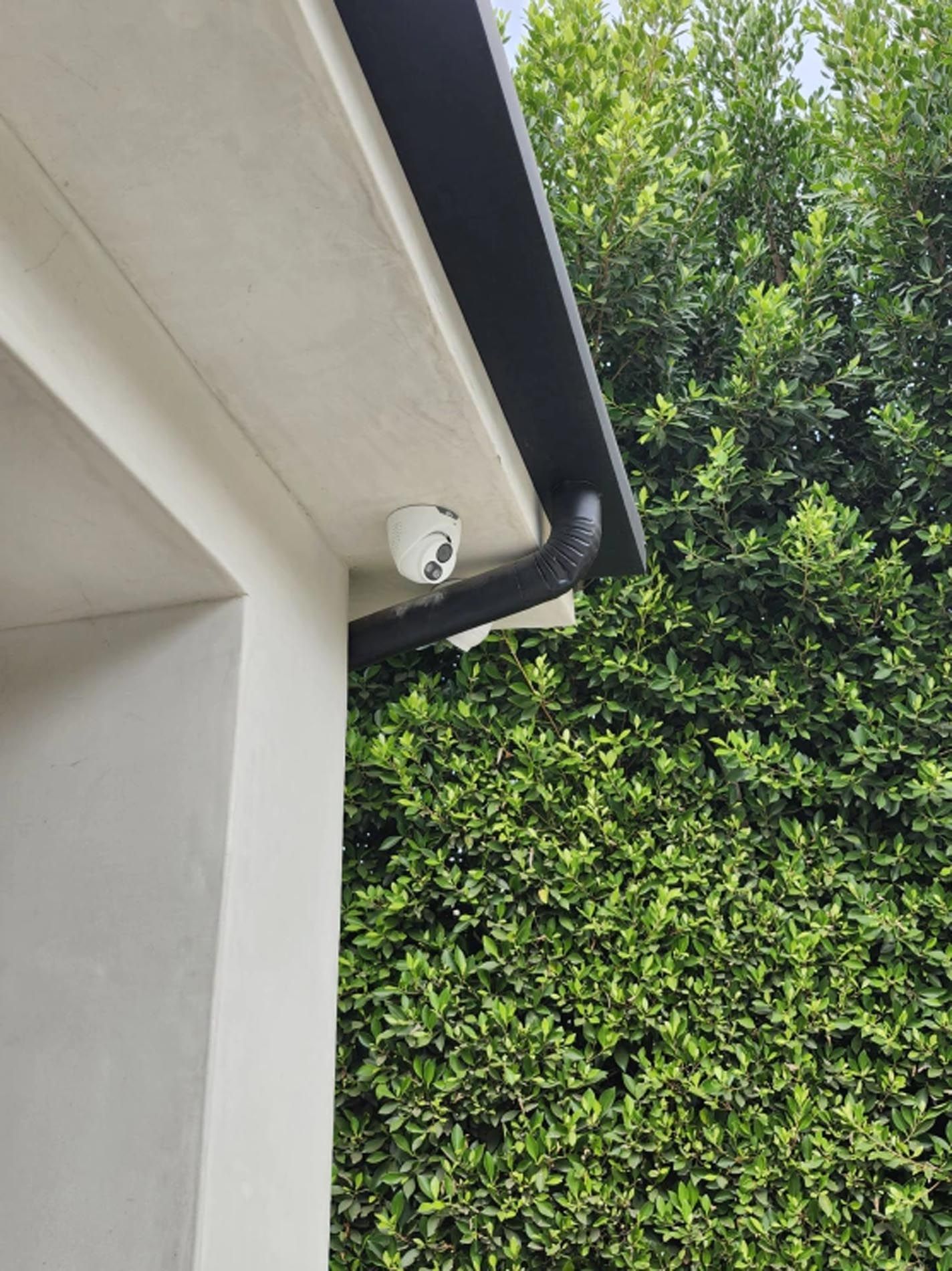 A security camera is mounted on the roof of a house.
