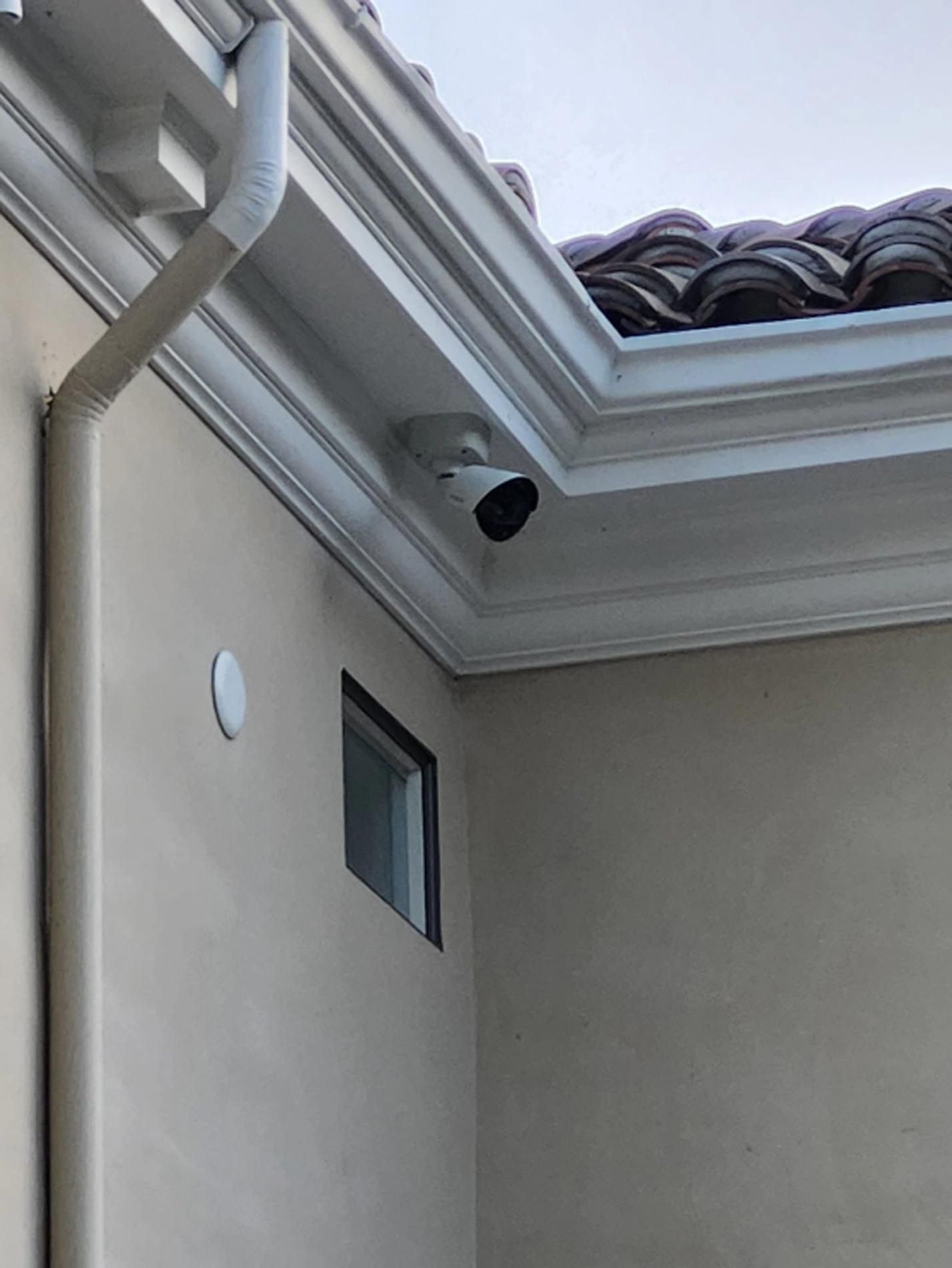A security camera is mounted on the side of a house.