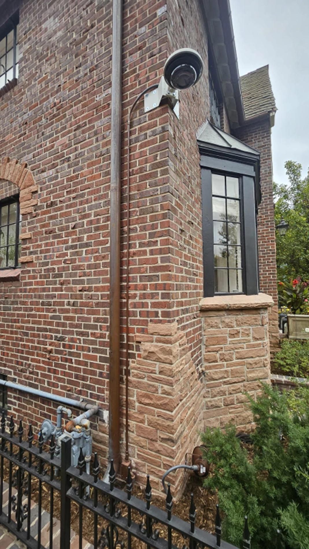 A security camera is mounted on the side of a brick building.