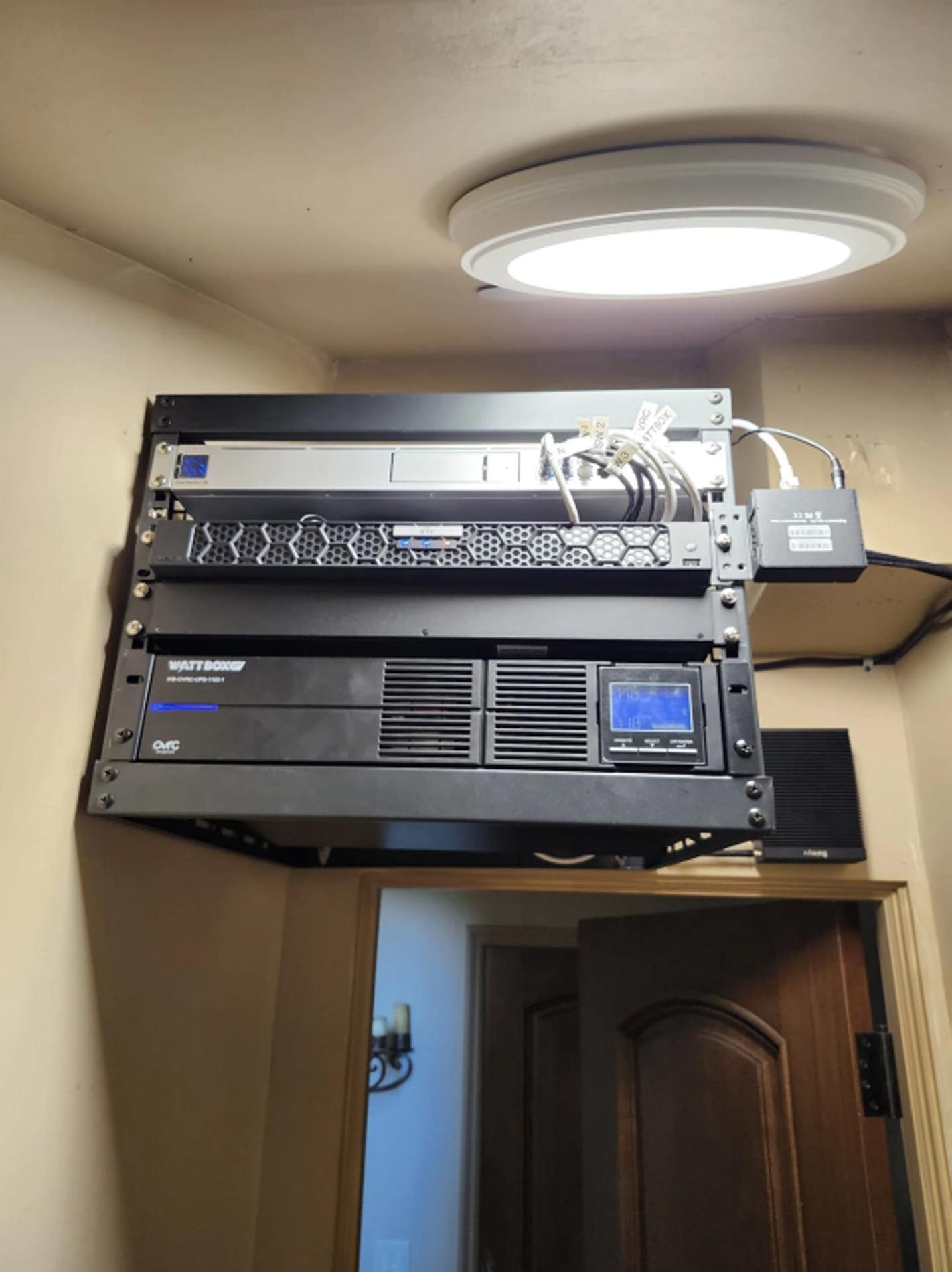 A rack of computer equipment is hanging from the ceiling in a room.