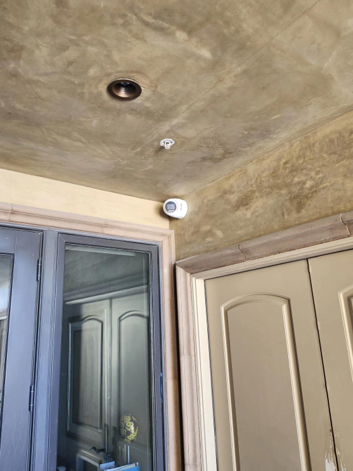 There is a smoke detector on the ceiling of the room.