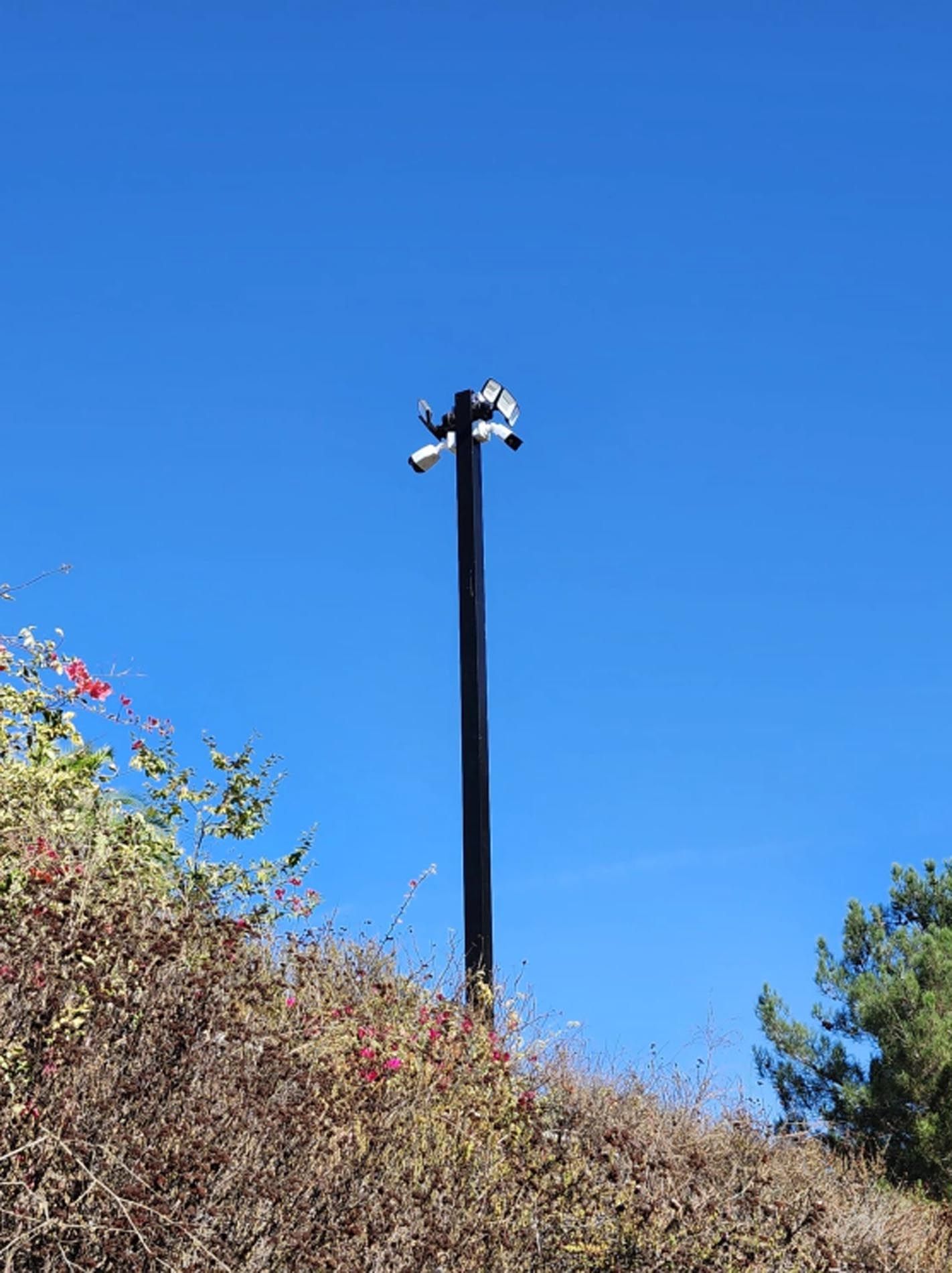 A pole with two cameras on it is sitting on top of a hill.