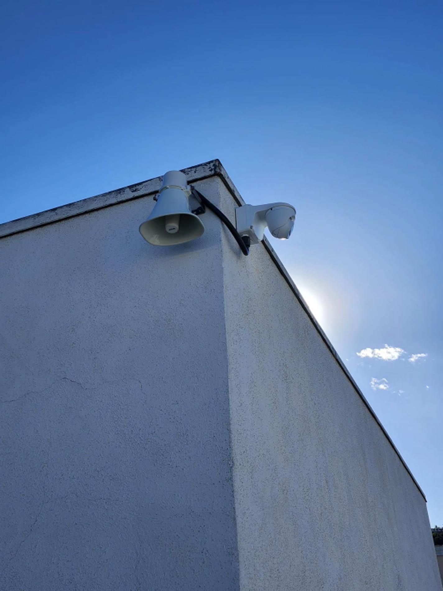 A white building with a speaker on the side of it