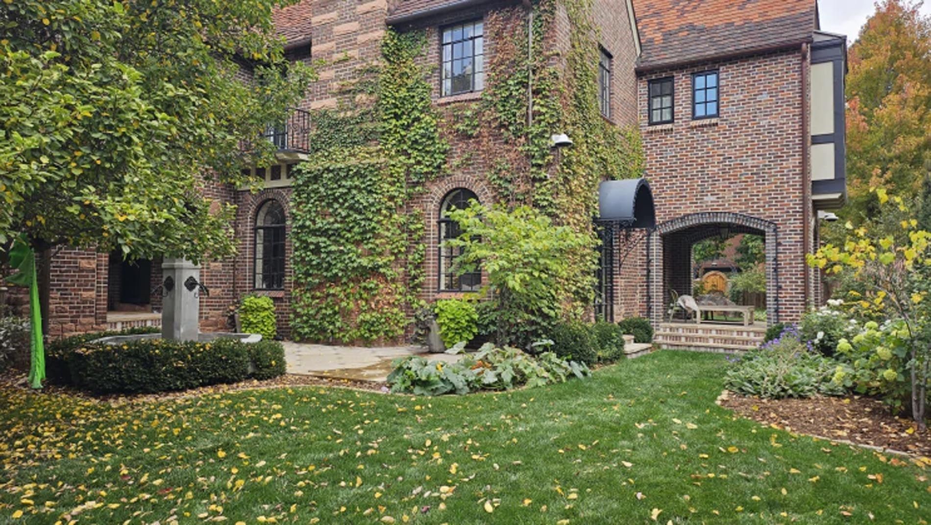 A large brick house with a lush green lawn in front of it.