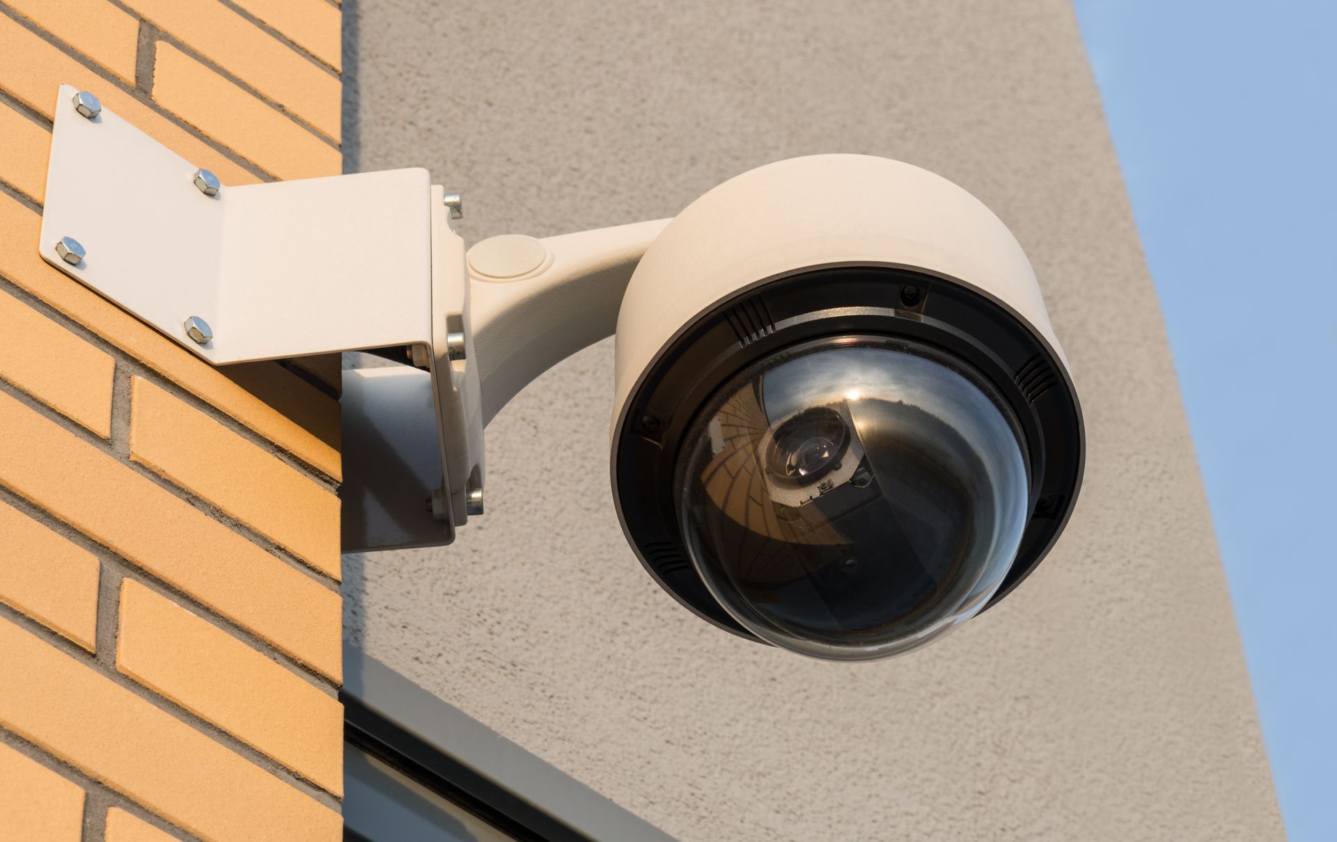 A security camera is sitting on a pole in front of a building.