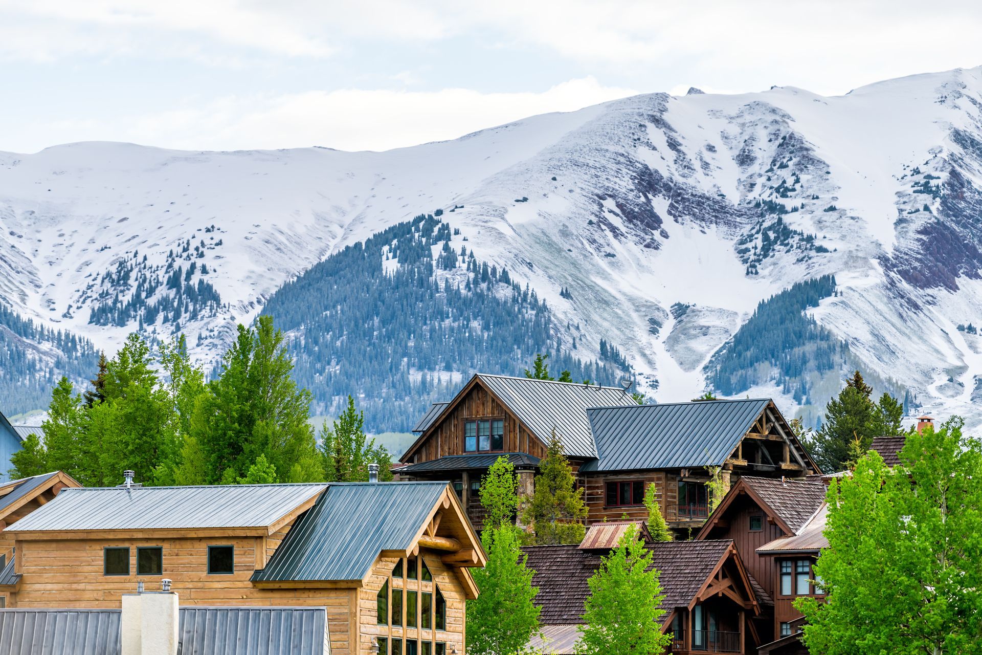 A group of houses with snowy mountains in the background.