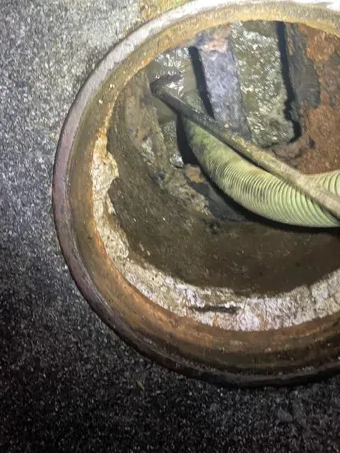 Inside view of a corroded metal pipe with a green cable running through it.