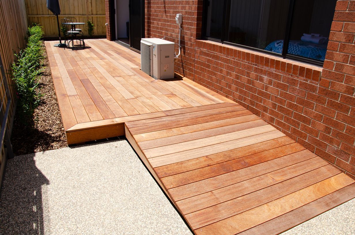A wooden deck with a ramp leading to it next to a brick building.