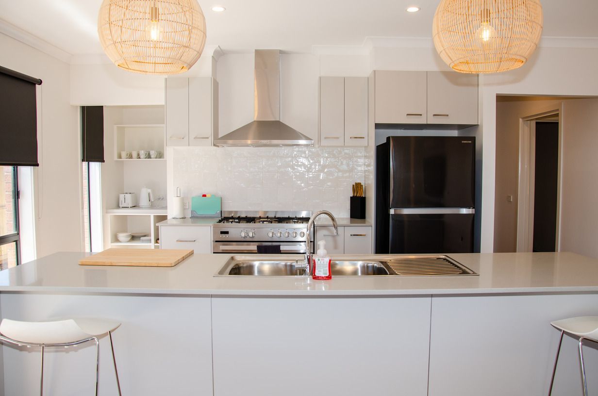 A kitchen with white cabinets and a black refrigerator
