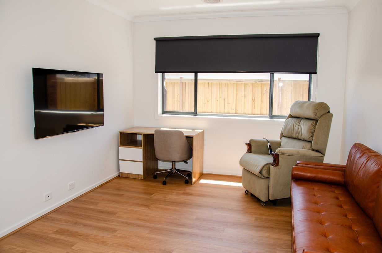 A living room with a couch , chair , desk and television.