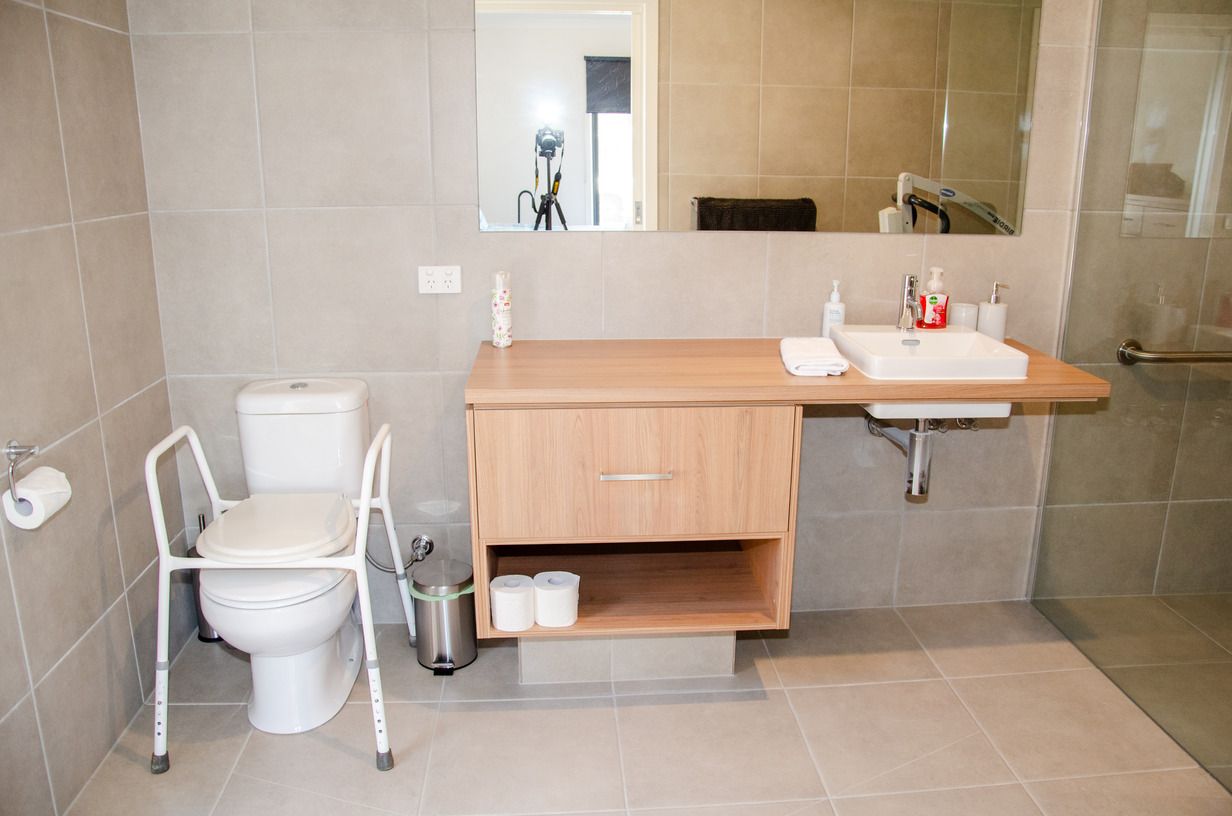 A bathroom with a toilet , sink and mirror.