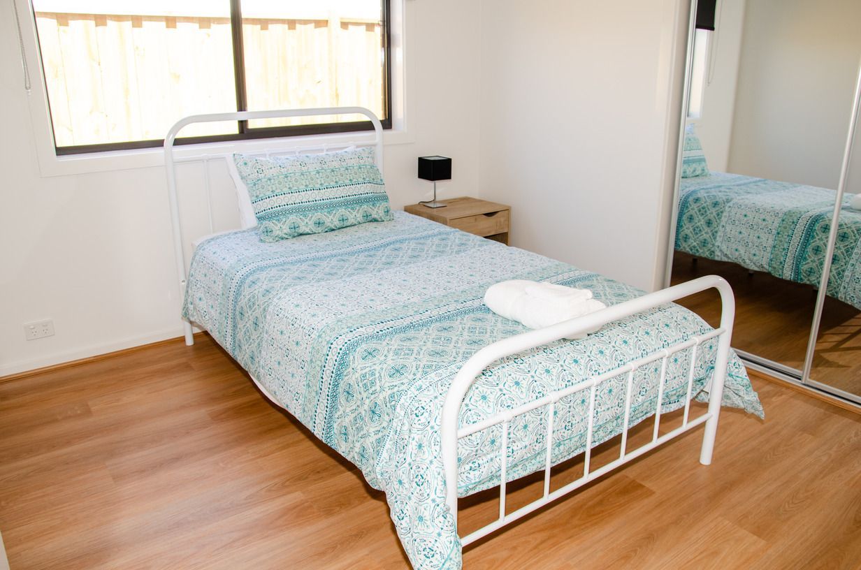 A bedroom with a single bed and a mirror.