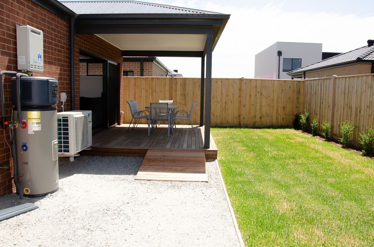 A patio with a table and chairs in the backyard of a house.