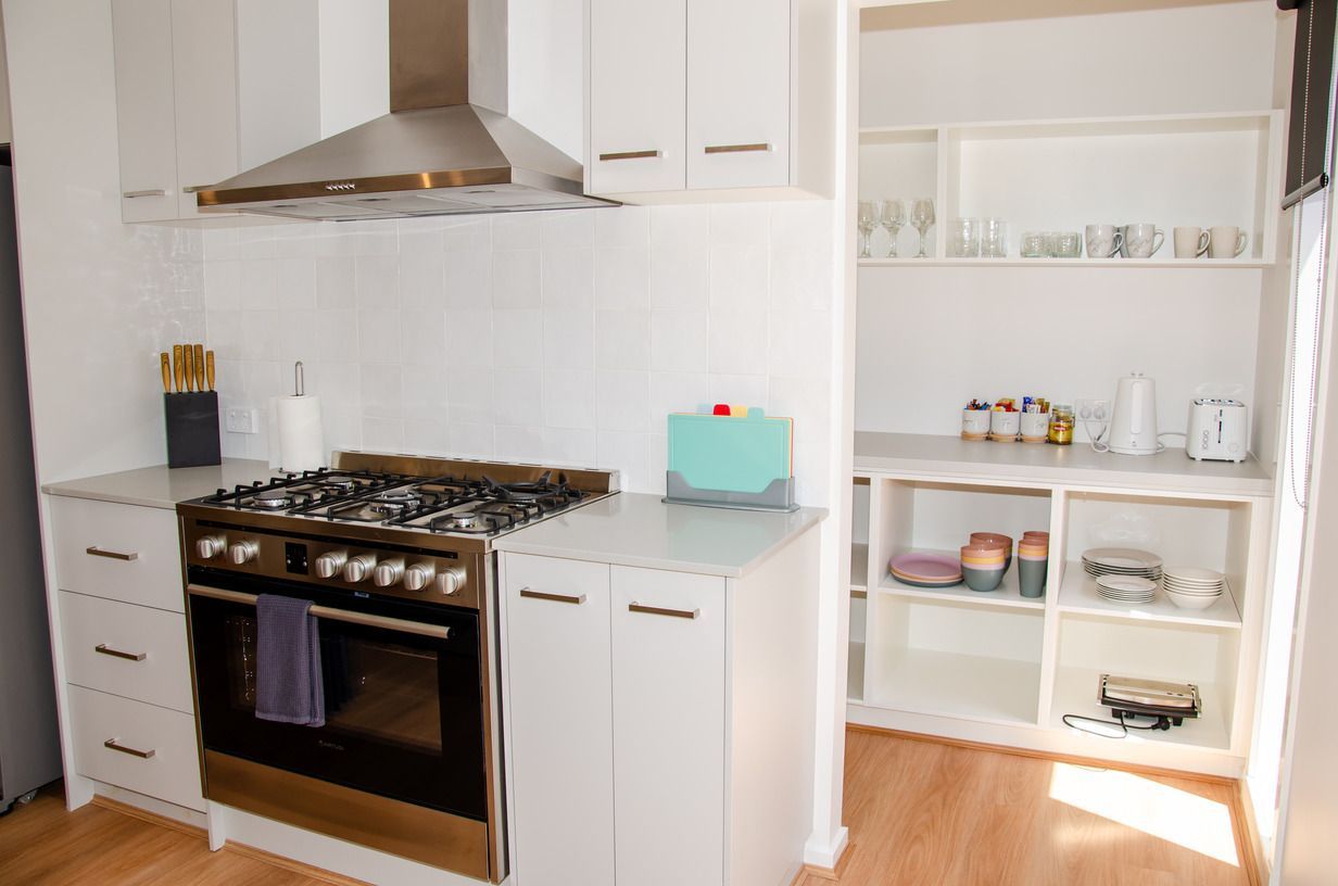 A kitchen with white cabinets and a stove top oven