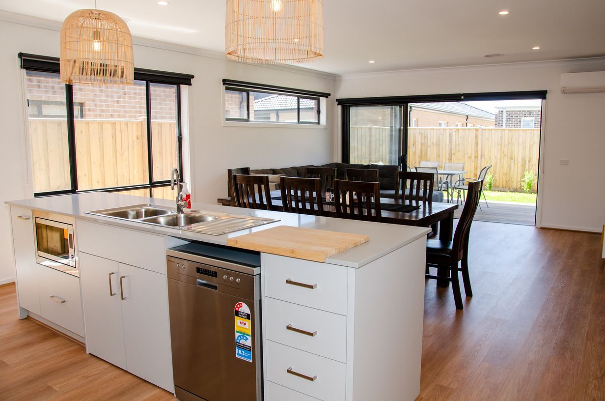 A kitchen with a large island in the middle and a dining room in the background.