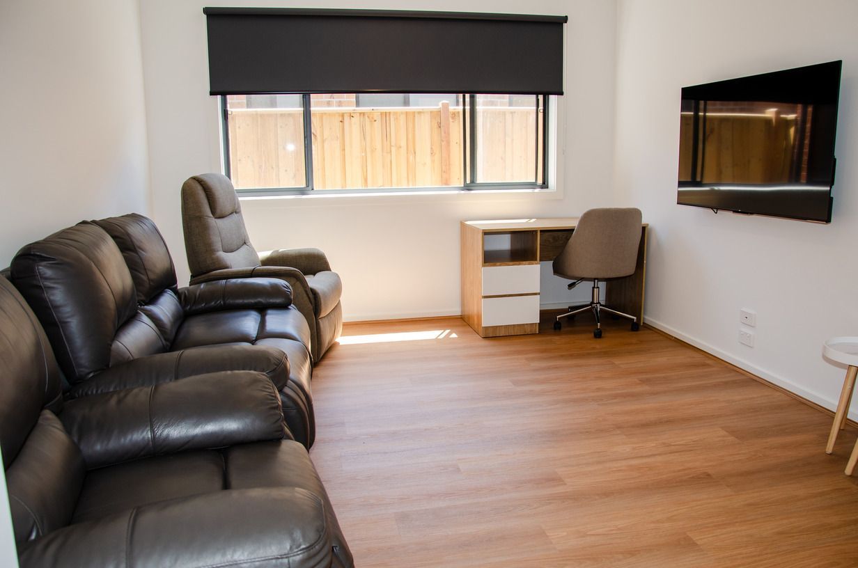 A living room with a couch , chair , desk and television.