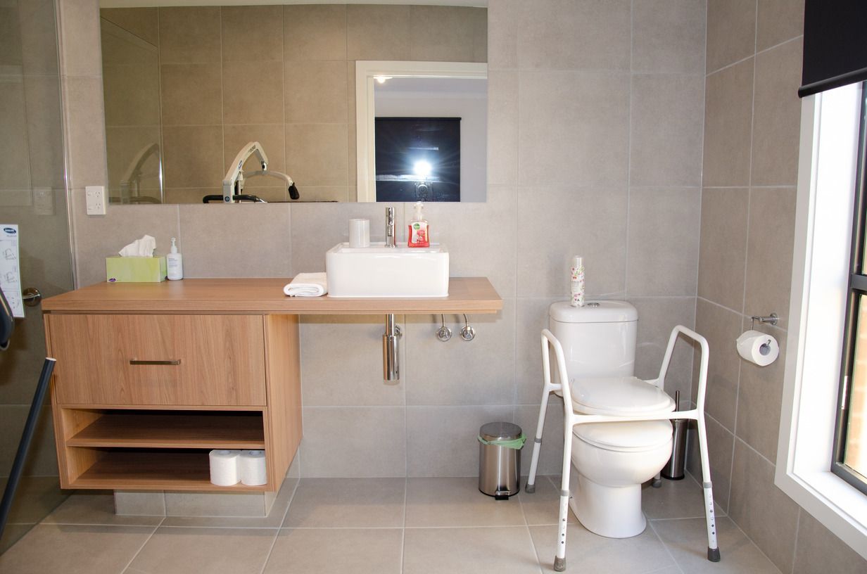 A bathroom with a toilet , sink and mirror.