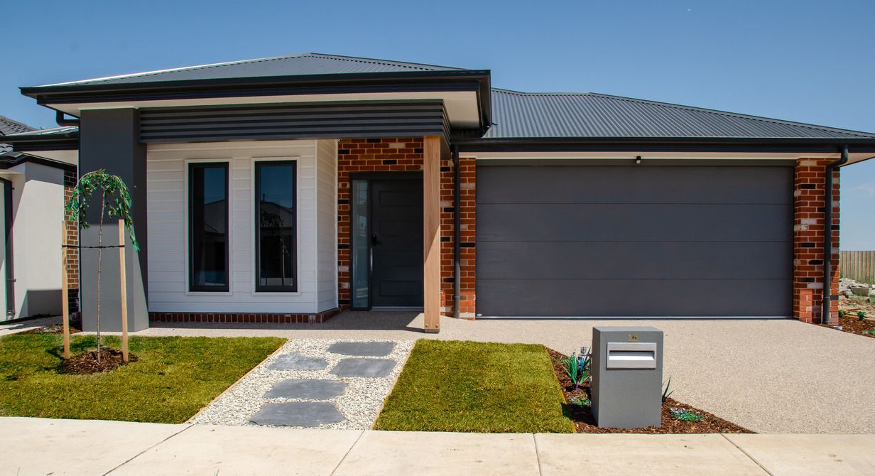 A modern house with a gray garage door and a mailbox in front of it.