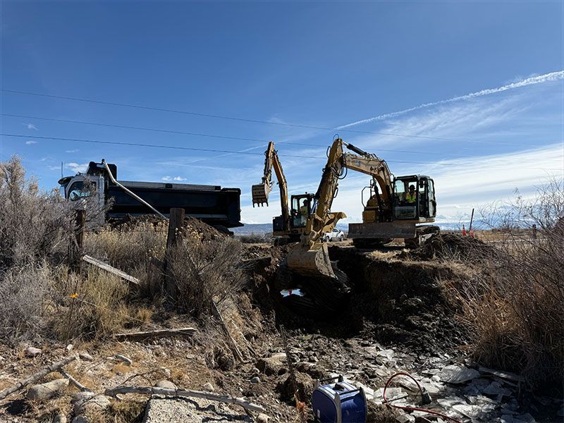 Two excavators digging, truck loading soil on a sunny day.