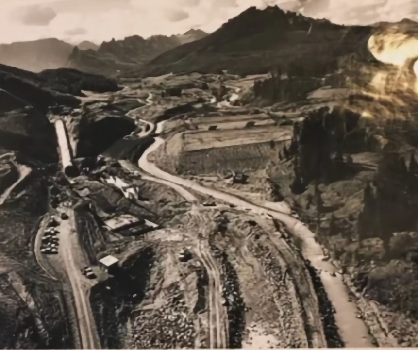 A black and white photo of a valley with mountains in the background