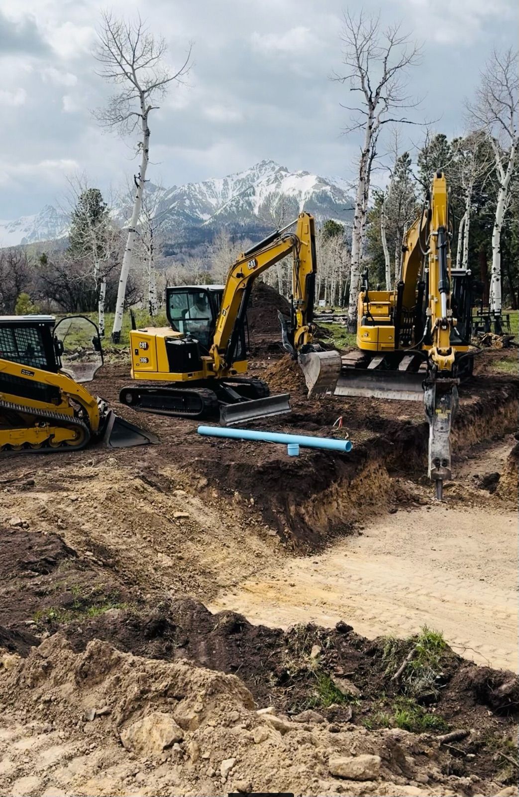 Two excavators are digging a hole in the dirt on a construction site.