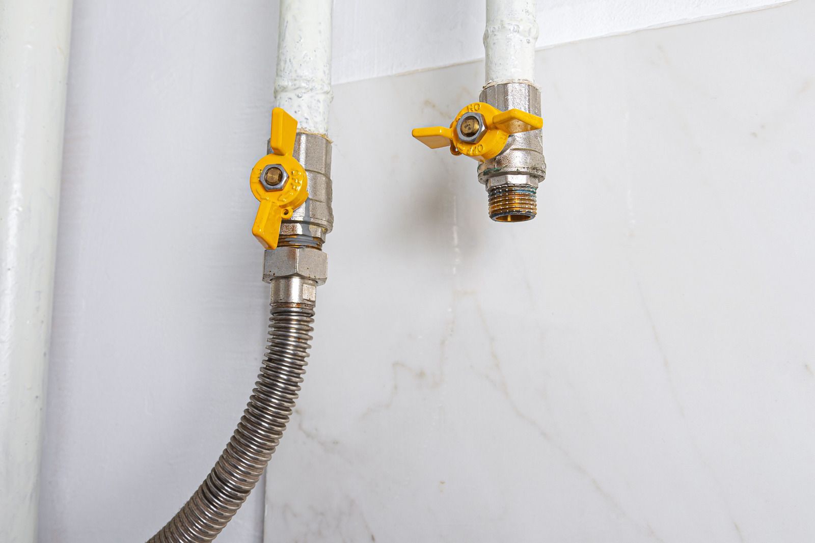 A close up of two gas pipes with yellow valves attached to them.