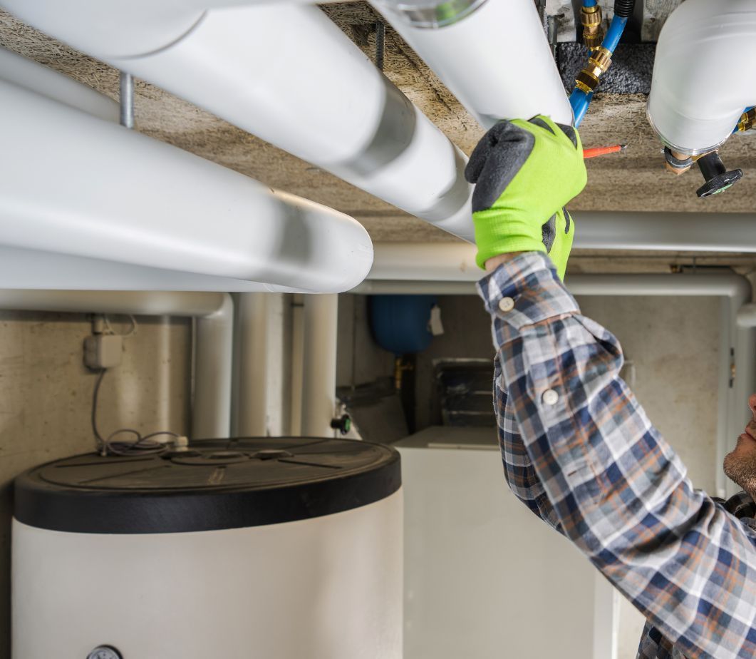 A man wearing green gloves is working on a water heater