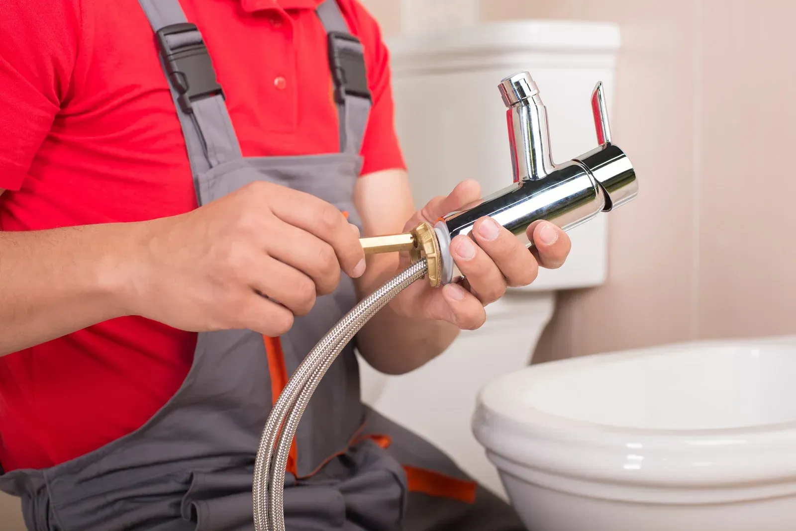 Plumber connecting a faucet to a water supply line in a bathroom.