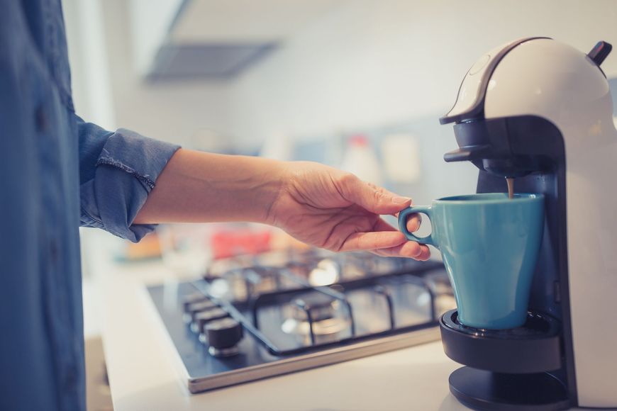 una persona versa una tazza di caffè da una macchina da caffè