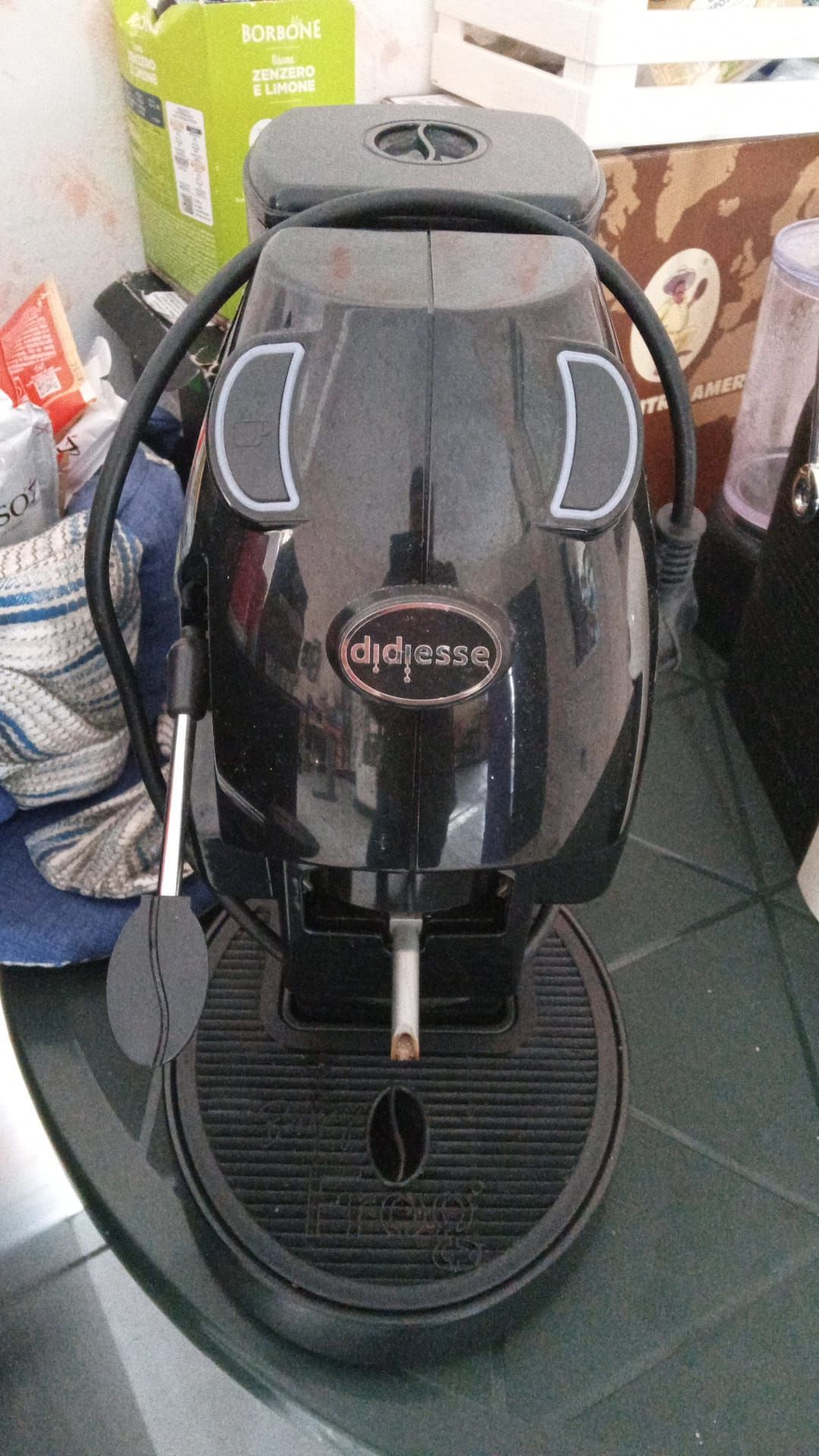 una macchina da caffè nera su un tavolo accanto a una scatola di caffè borbone