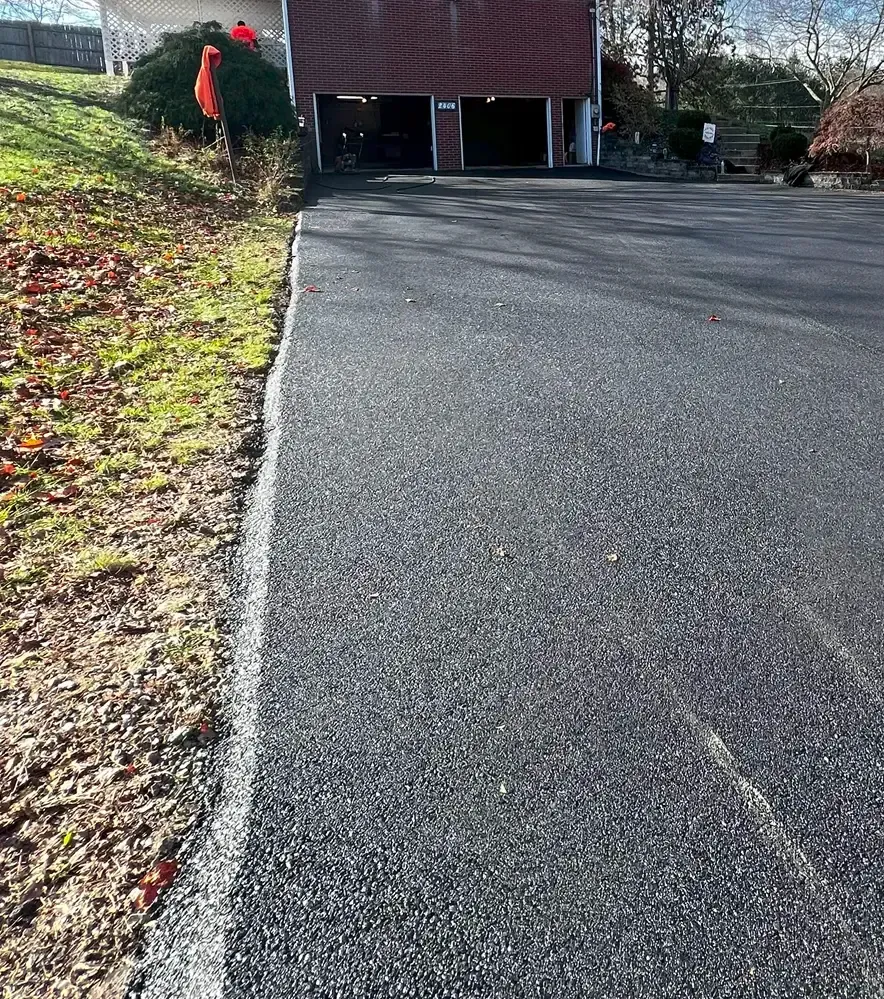 A driveway leading to a garage with a brick building in the background.