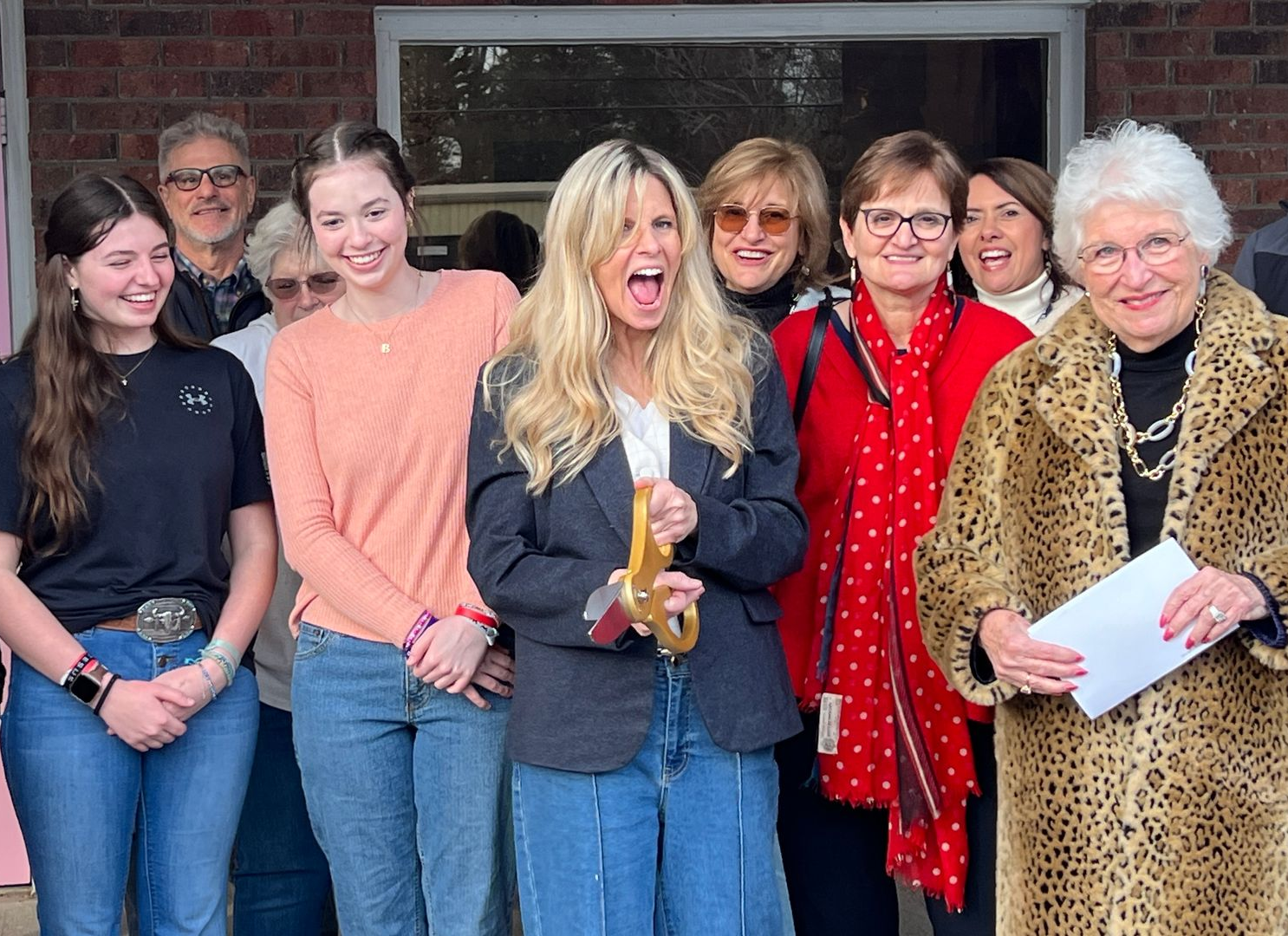 Group of people celebrating outdoors; woman holding key, smiling widely, others watch.